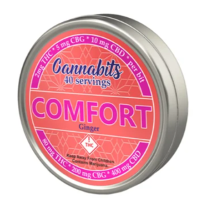 A round tin container with a pink label that reads Cannabits Comfort Ginger and indicates 40 servings. The label also mentions THC, CBG, and CBD content. The product appears related to cannabis.