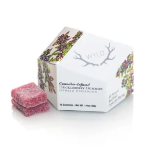 Hexagonal box labeled Wyld with floral design, containing cannabis-infused huckleberry gummies. Three pink gummies are placed beside the box. The packaging notes they are hybrid enhanced, all-natural, and perfect for sharing.